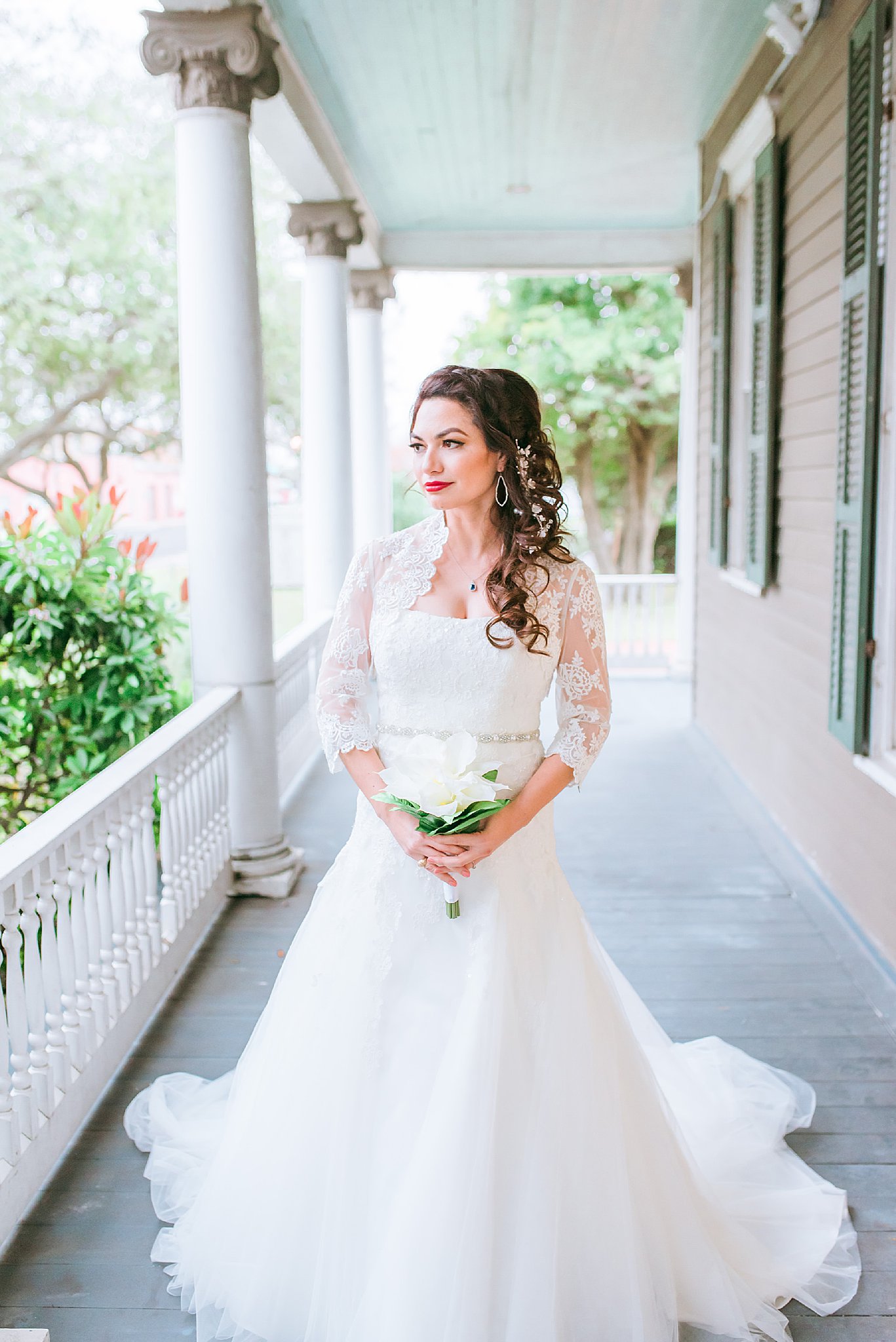 Bride in wedding dress holding a white bouquet on the patio of the Heritage Park house in Corpus Christi, Texas