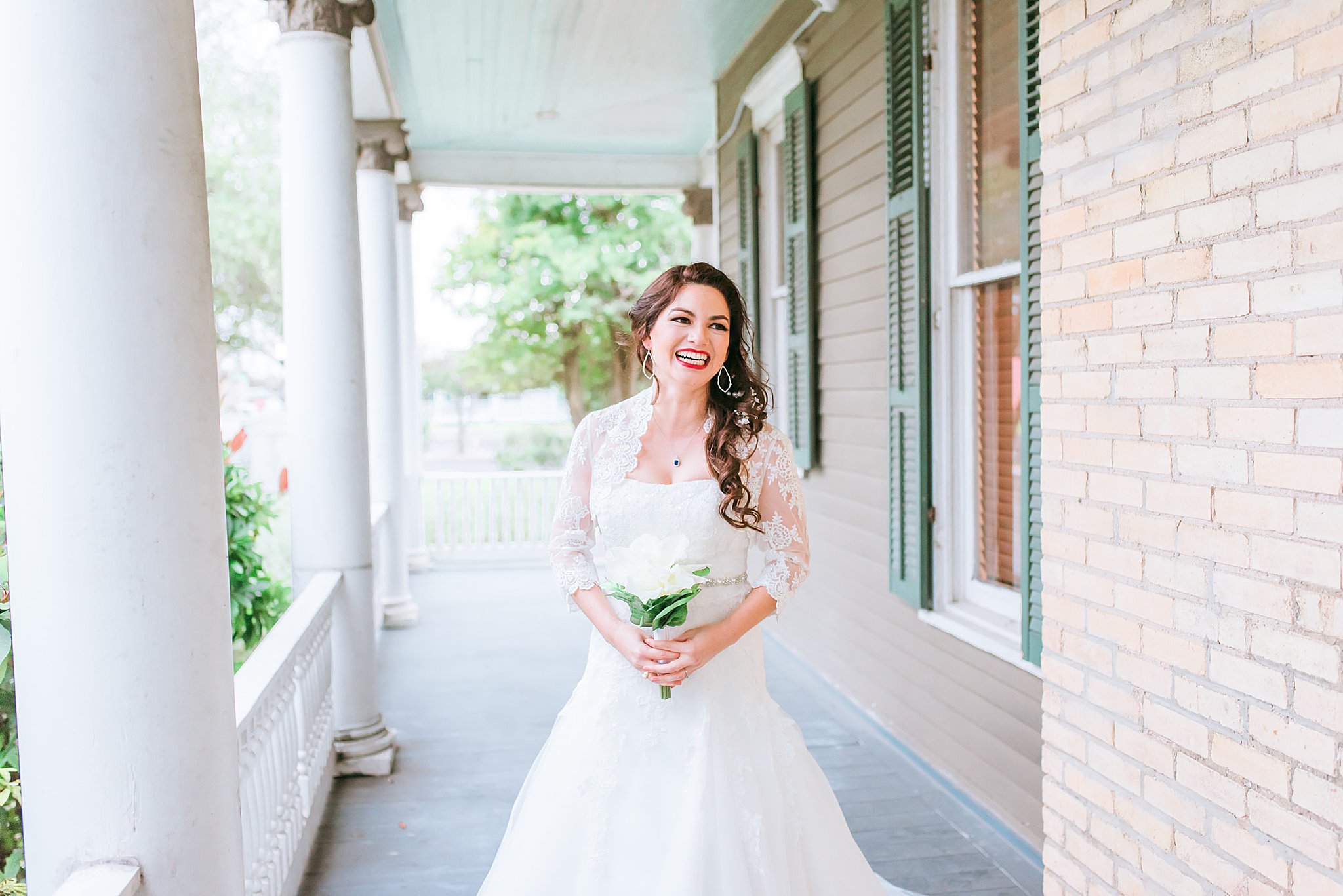 Bride in wedding dress holding a white bouquet on the patio of the Heritage Park house in Corpus Christi, Texas